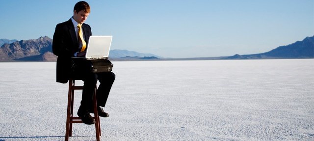 man in a suit using a laptop in field